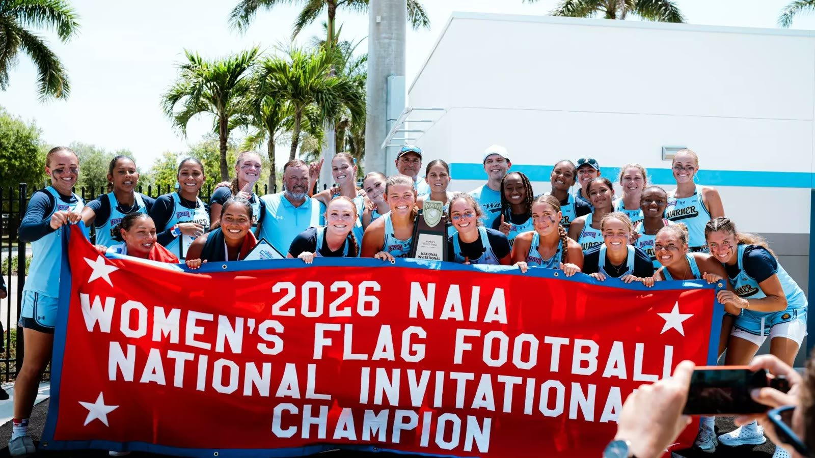 Warner University team with the 2026 NAIA Women's Flag Football National Invitational Champion banner